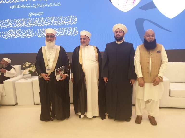 مع عدد من العلماء المشاركين أمام منصة المؤتمر